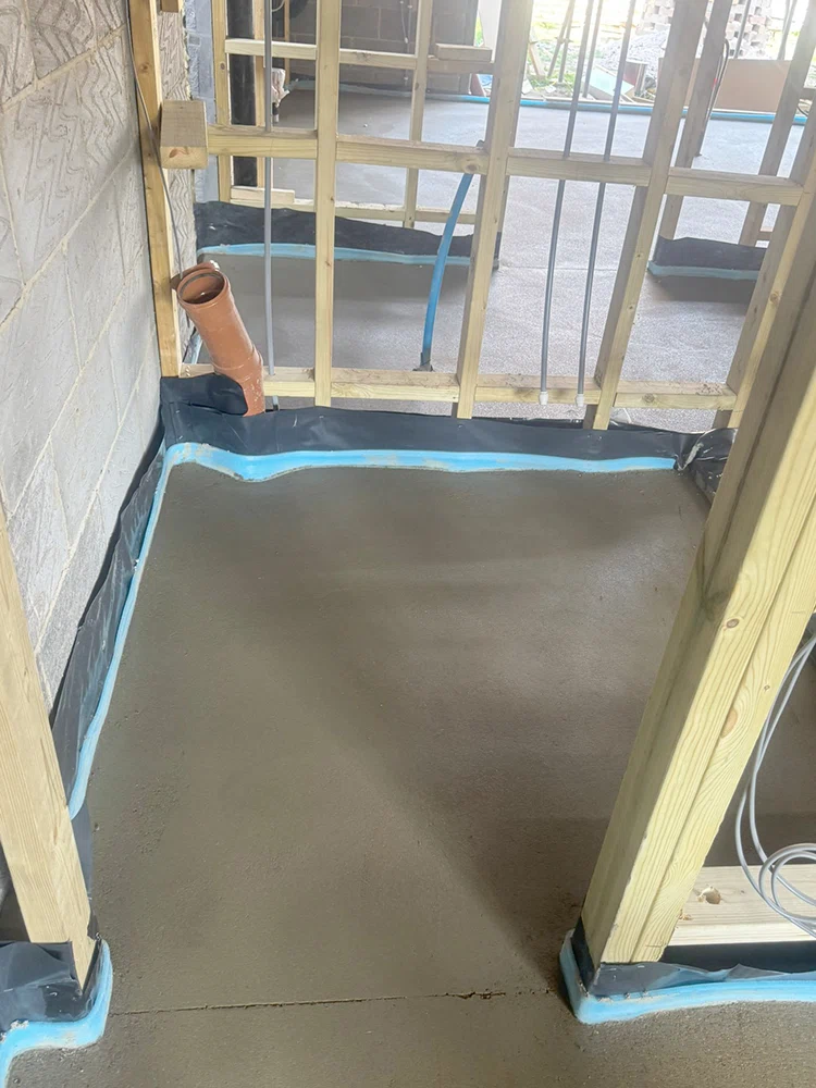 Fresh floor screed laid against a blue perimeter edge strip in a new build