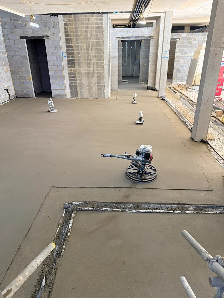 Sand and cement screed being power floated in a new build with the power float left mid-room