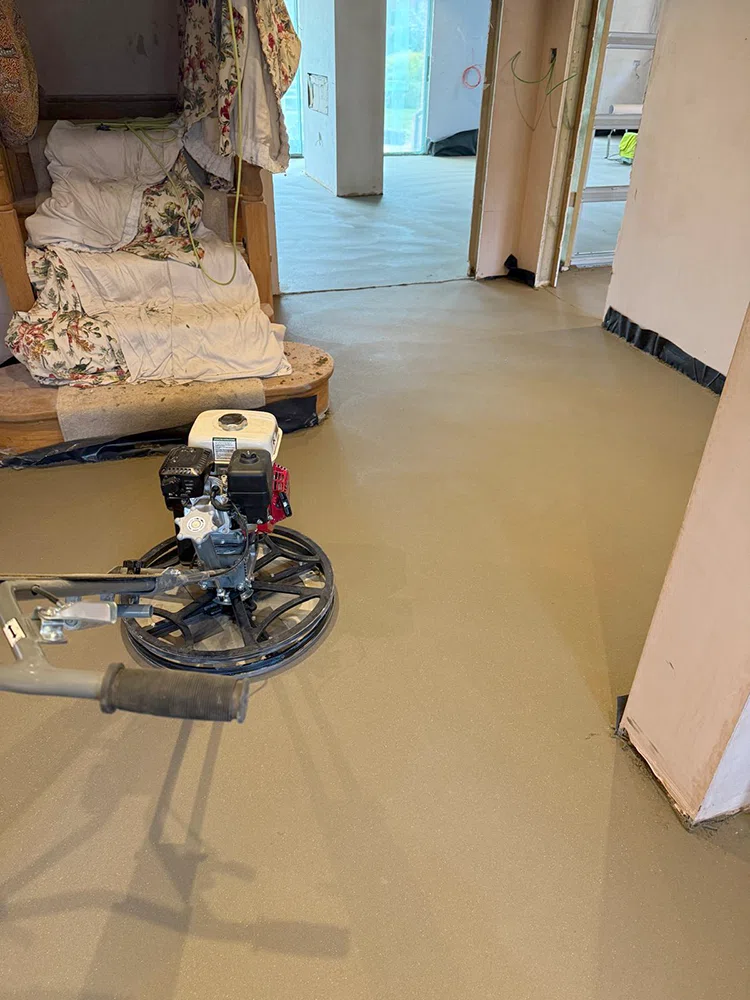 Power float working a sand and cement screed in a residential room