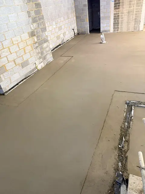 Finished screed with pipe entry visible at the wall