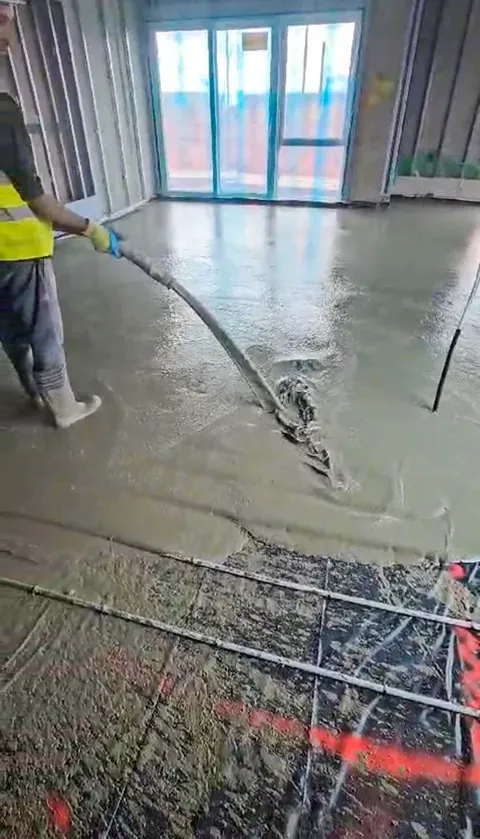 Liquid screed being poured over underfloor heating pipes