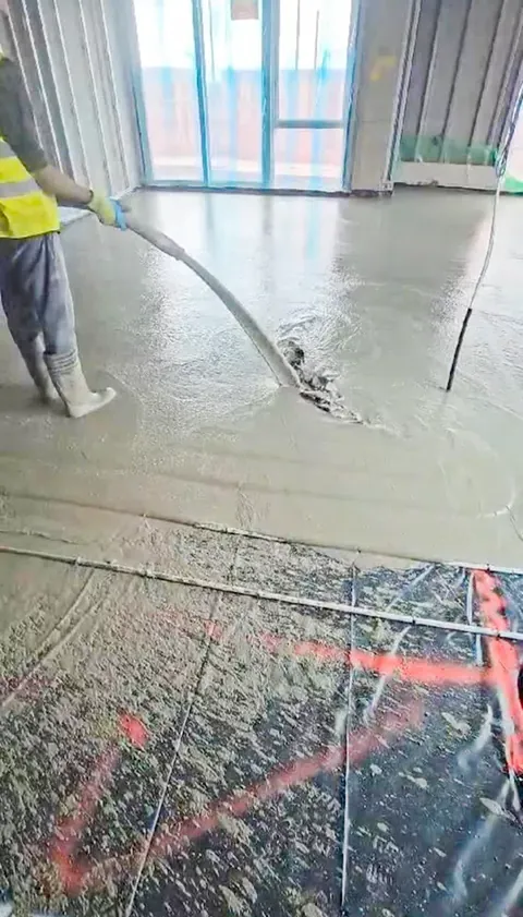 Liquid screed being pumped over underfloor heating pipework