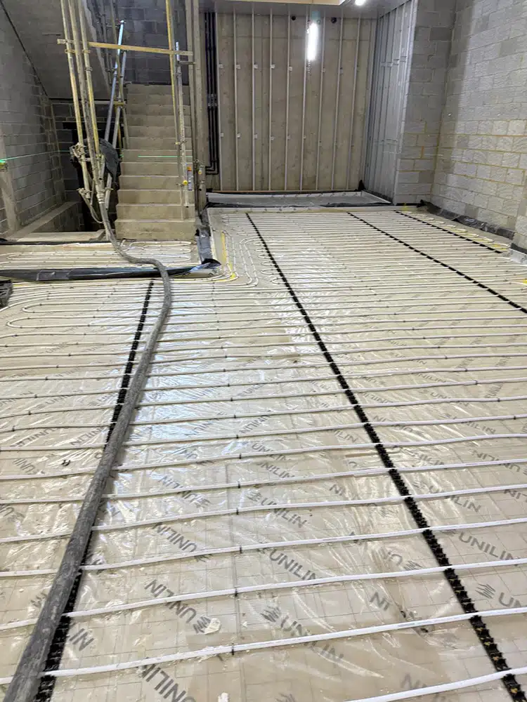 Underfloor heating pipes clipped down along a long ground floor ready for screeding